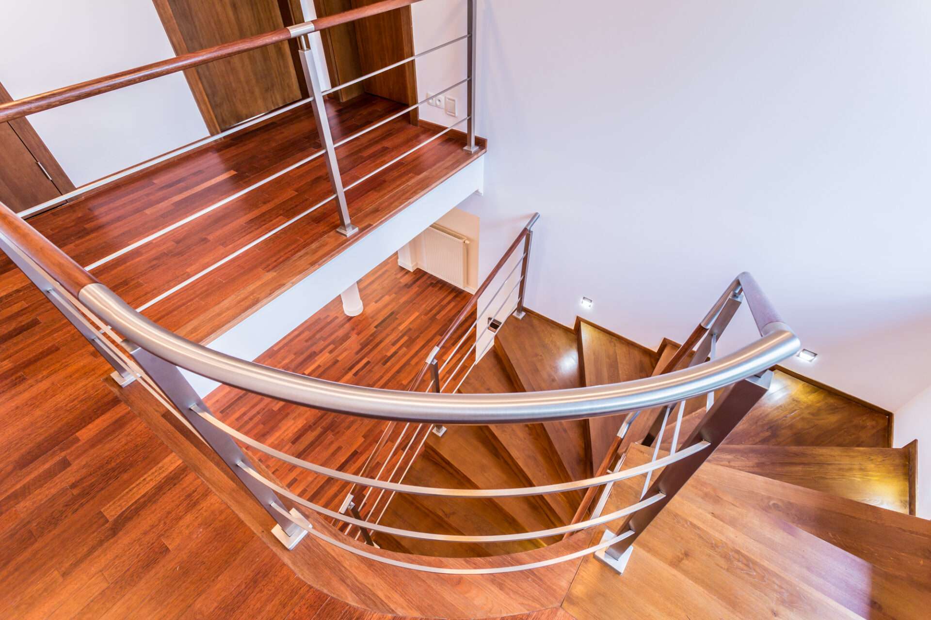 spiral stainless steel railing alongside wooden stairs