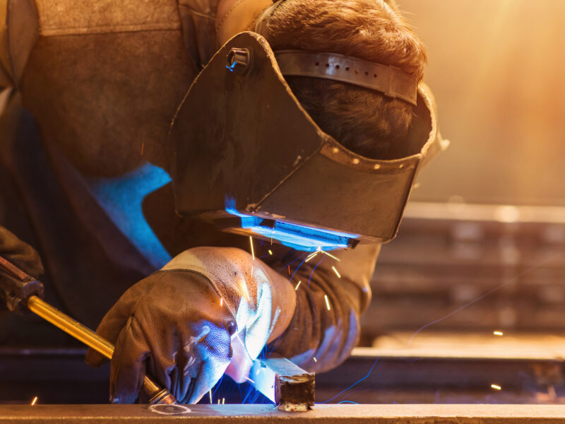 Man wearing protective mask fabricating steel
