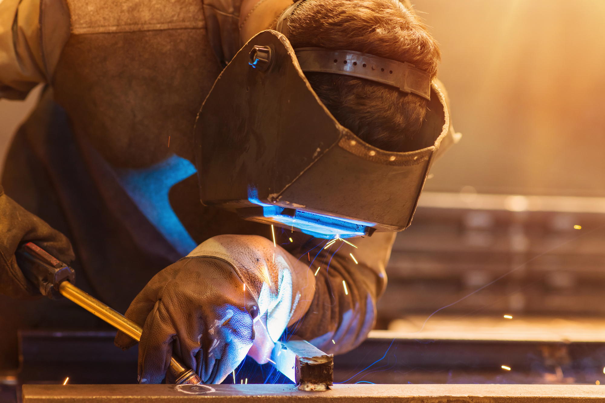 Man wearing protective mask fabricating steel
