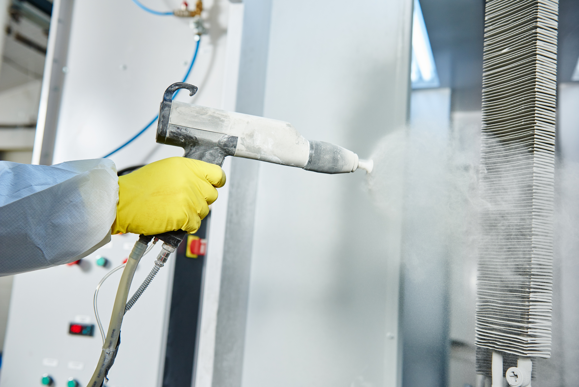 fabricator applying powder coating to metal with spray tool
