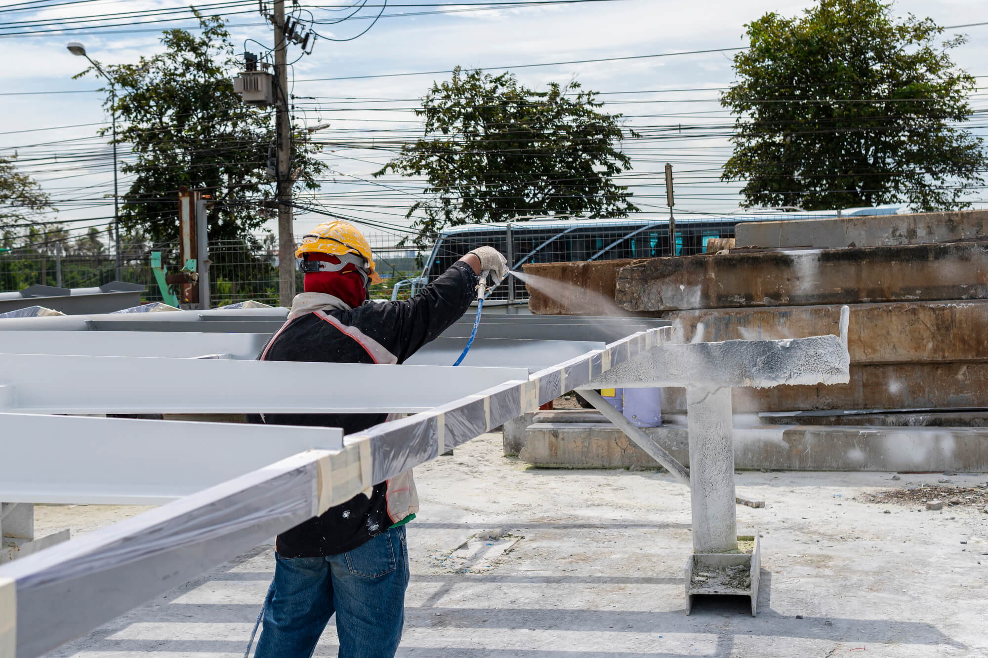 The painter is working to fireproof paint on steel structure with spray gun