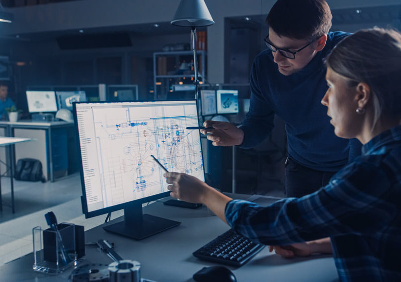 CAD Software Man and woman pointing at a CAD drawing on a computer screen.