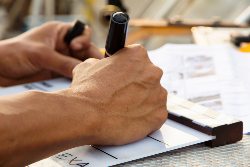 man writing on piece of paper with black pen